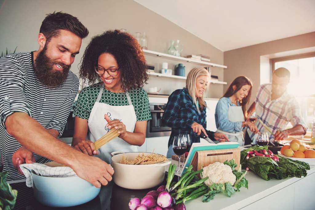 5 of Our Best Self Care Tips for Travelers Five friends cheerfully cooking for an upcoming party
