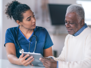 A healthcare professional using a tablet to interact with a patient.