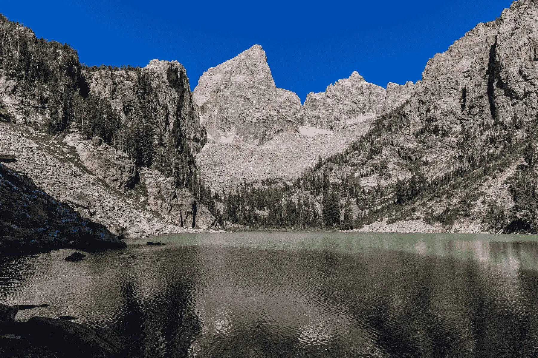 closeup view of a mountain with a lake below, surrounded by trees