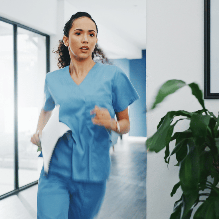 Healthcare professional in blue scrubs moving quickly through a healthcare facility while carrying documents.